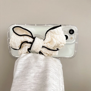 White fabric bow phone socket holder with black trim on a transparent phone case