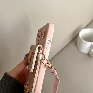 Detail of pink floral iPhone case with tweed wallet, bow decoration and leather strap