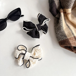 Detail of fabric bow phone grips in black and white with pleated texture and stylish accessories