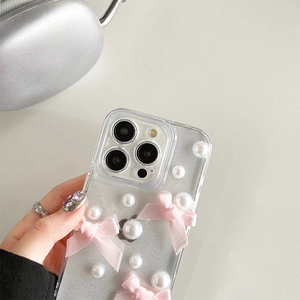 Détail de la coque iPhone pailletée avec nœuds en soie rose et perles blanches de style