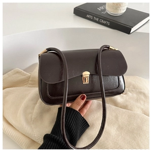 Vintage dark brown matte leather baguette bag with gold buckle on a beige background