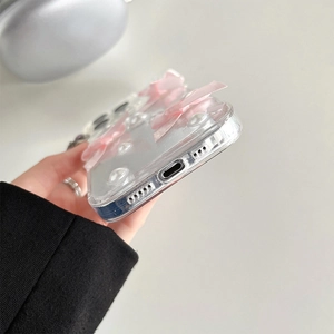 Gros plan des nœuds roses et perles sur une coque transparente à paillettes pour iPhone