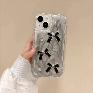 Détail de la coque iPhone pailletée avec vagues argentées, nœuds noirs et strass