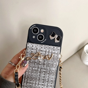 Detail of tweed card pocket on black iPhone case with rhinestone bow and gold chain