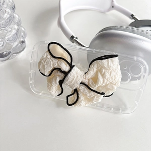 Detail of transparent phone case featuring a large white fabric bow with black edge trim