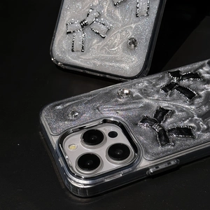 Macro detail of glitter iPhone case with metallic bow and rhinestone embellishments