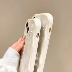 Detail view of wavy edge cream phone case with 3D butterfly and pearl accents