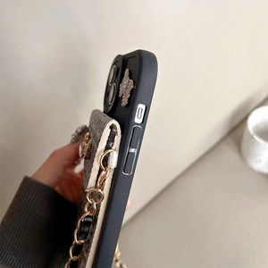 Detail view of iPhone card holder case with braided texture flap and gold butterfly chain