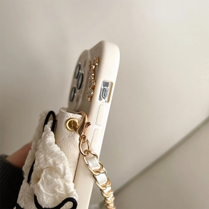 Close-up of litchi texture phone case with bow buckle, gold chain, and teddy bear detail