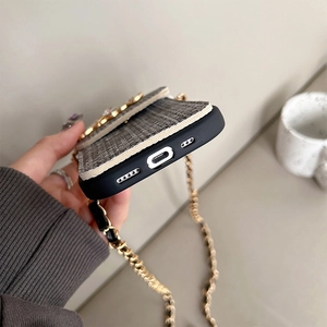 Detailed view of luxury black and white tweed iPhone case with gold buttons and chain strap
