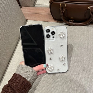 Custodia per iPhone glitterata con fiori di perle 3D e strass tenuta in mano