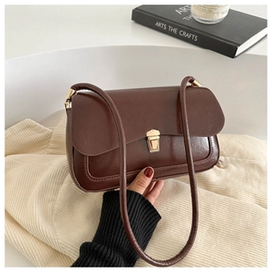 French vintage dark brown faux leather shoulder bag with a gold clasp being held