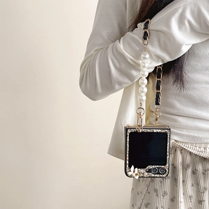 Detail of luxury foldable phone case featuring white pearls, gold chain and glitter