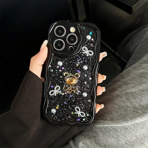 Glitzernde schwarze iPhone-Hülle mit Strasssteinen, goldenem Bären und Schleifen in der Hand