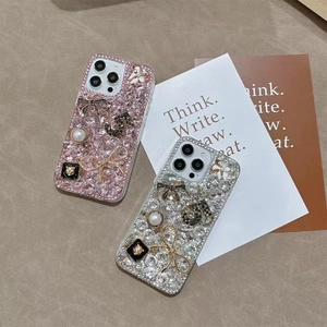 Close-up of luxury iPhone case featuring rhinestones, pearls and bow-tie decorations