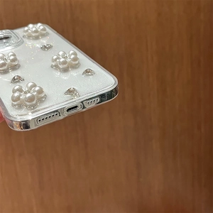 Dettaglio ravvicinato di fiori di perle 3D e strass su una cover glitterata per iPhone