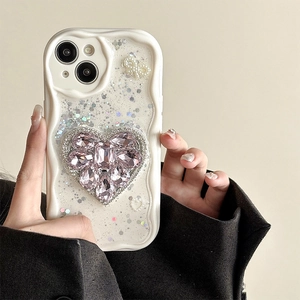 Detail of iPhone case featuring large pink crystal heart and pearl bow on glitter background