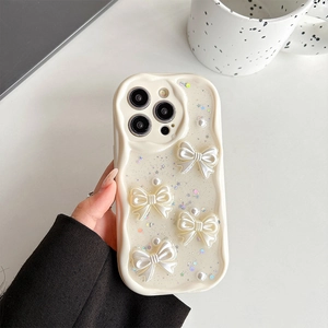Detail of cream white wave-edge phone case with 3D pearlescent bows and glitter accents