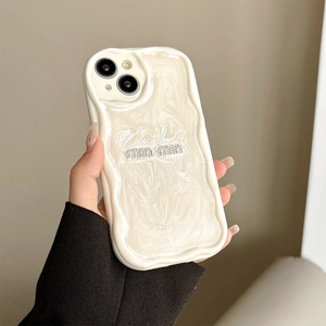 Detailed view of cream-colored wavy phone case with pearlescent texture and rhinestone logo