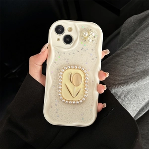Detail of a wavy phone case with glitter, pearls, and a gold tulip emblem held by a hand