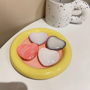 Detail of four colorful gradient crystal heart-shaped phone grips on a yellow plate