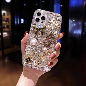Close-up of luxury phone case with glittering rhinestones and bow charms held in hand