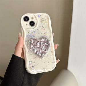 Detail of cream wavy iPhone case featuring a pink rhinestone heart and pearl bow accents