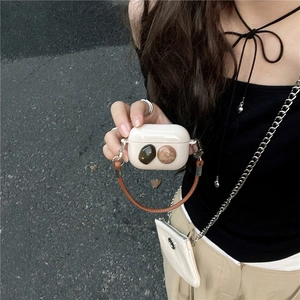 Close-up of cream AirPods Pro case with gem accents and brown leather hand strap.