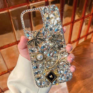 Detailed luxury phone case featuring sparkling rhinestones, pearls, and a black bow