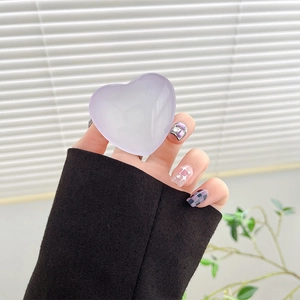 Close-up of translucent purple crystal heart phone grip being held against a window