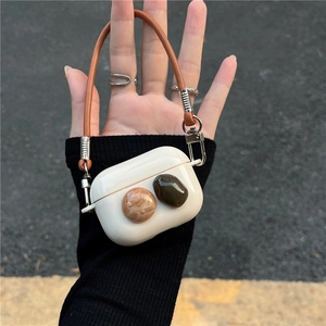 Detailed view of cream AirPods Pro silicone case with faux gemstone accents and leather strap