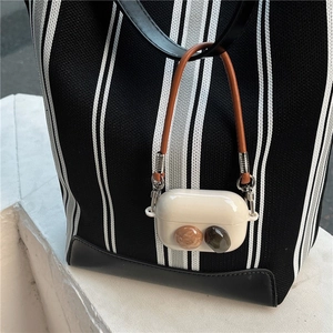 Detail of gemstone-embellished silicone AirPods Pro case with a brown leather carry strap