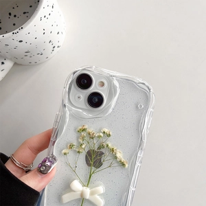 Close-up of clear glitter iPhone case with 3D white bow and dried flowers detail