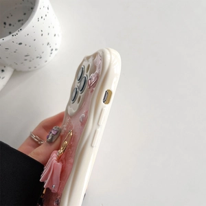 Close-up of iPhone case with 3D pink bow, pearls and ballerina charm on wavy edge
