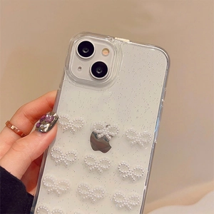 Close-up of glittery clear phone case with small white pearl bow decorations