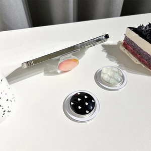 Collapsible magnetic phone grip set in pink gradient and shell pattern on a clean desk