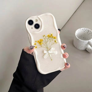 Close-up of glitter iPhone case with 3D white bow and yellow dried flowers detail