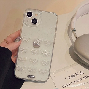 Detailed view of clear glitter iPhone case with pearl bow patterns and hand-held styling