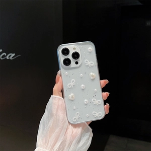 Transparent iPhone case with pearls, silver glitter, and bowknot decorations on hand