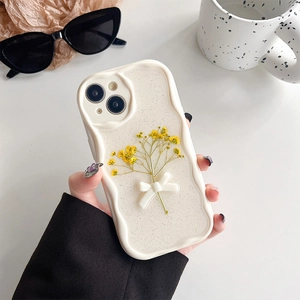 Close-up of wavy cream iPhone case with dried yellow flowers and 3D white bow tie detail