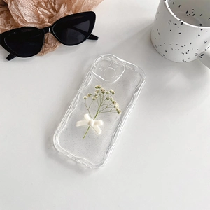 Detail of glitter phone case with white dried flowers and a 3D ribbon bow ornament