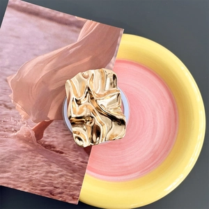 Detail of golden plated irregular rippled phone grip on artistic ceramic plate