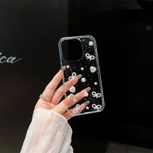 Close-up of clear phone case featuring 3D white pearls, hearts, and ribbon bow decor