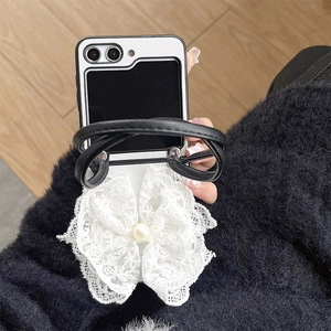 Detail of Galaxy Z Flip case with white lace bow and faux pearl on black leather strap