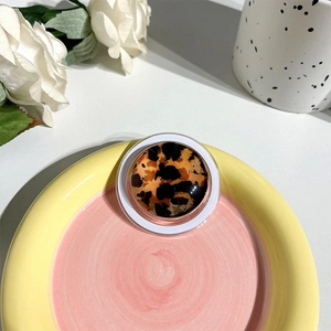 Close-up of a round leopard print phone socket grip on a decorative ceramic plate