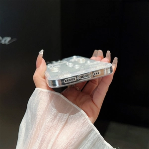 Close-up of clear phone case with white pearls and silver glitter held by hand