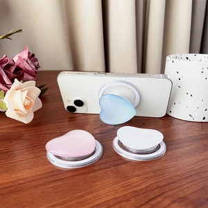 Detail magnetischer Herz-Handyhalter in Pastellblau und Rosa auf weißem Smartphone