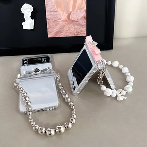 Detail of transparent Galaxy Z Flip case with metallic bow and pearl bead handle strap