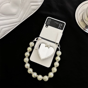 Detail of white cross-grain leather phone case with heart mirror and pearl strap