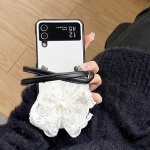 Detailed close-up of white lace bow and faux pearl on luxury leather folding phone case